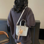mini handbag with textured design and fluffy pendant